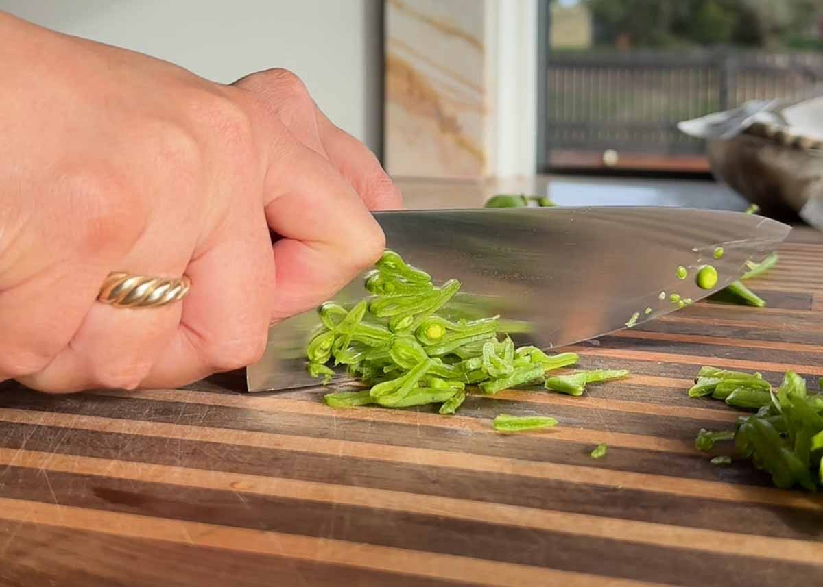 Sliced snow pea salad with honey mustard dressing and fresh herbs in bowl