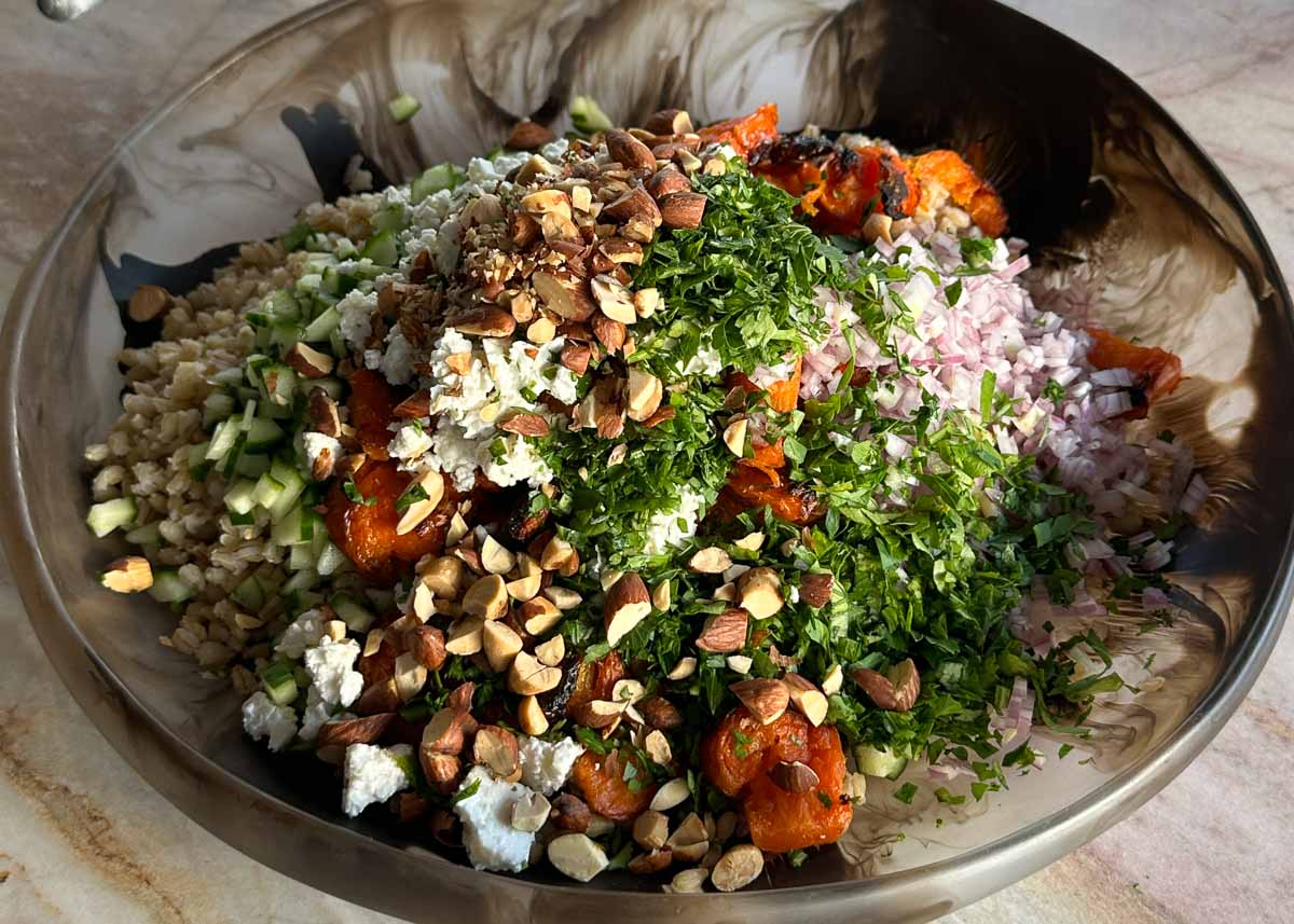 Ingredients for smashed carrot salad with honey mustard pork including pork tenderloin, carrots, pearl barley, feta, cucumber, herbs and almonds.