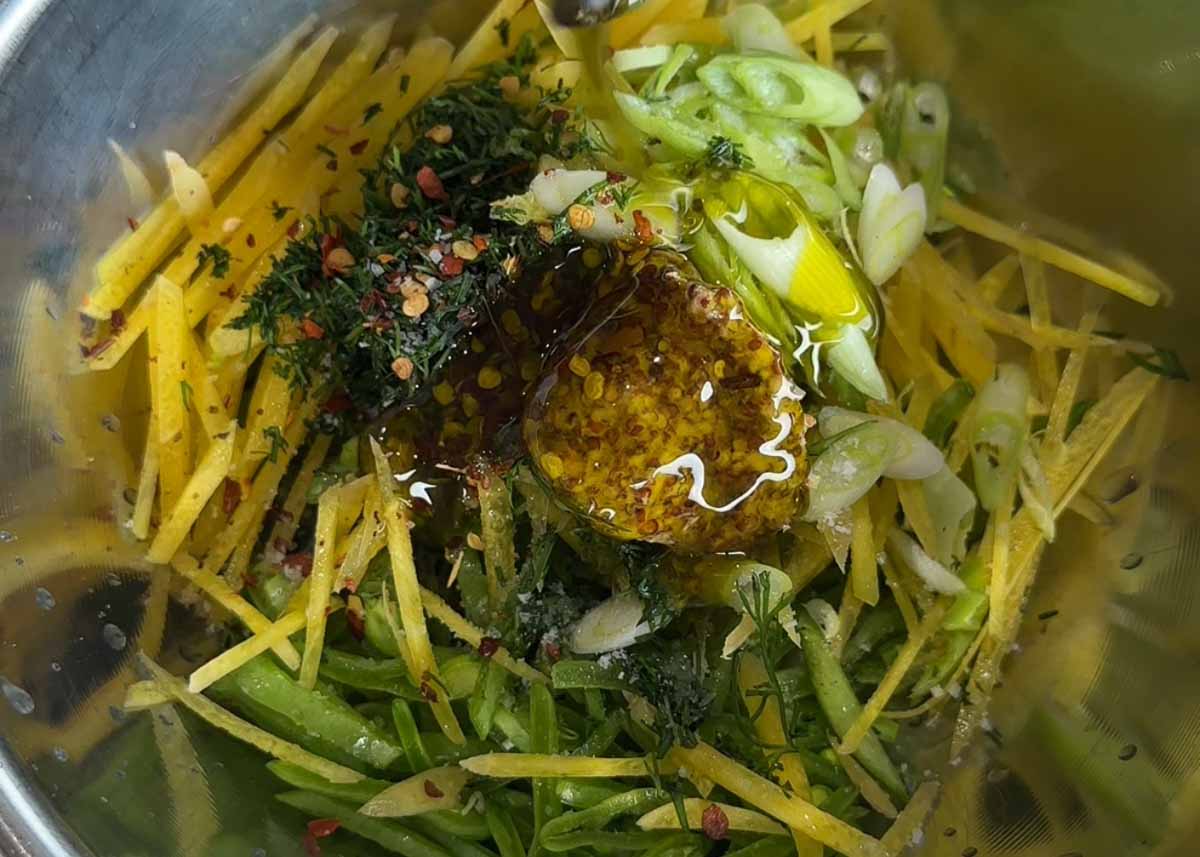 Sliced snow pea salad with honey mustard dressing and fresh herbs in bowl