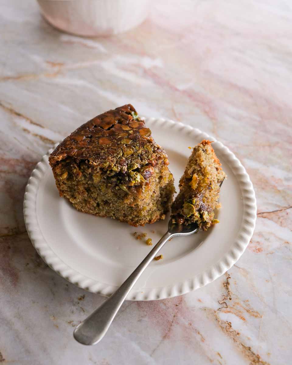Slice of spiced pistachio upside down cake served on a plate.