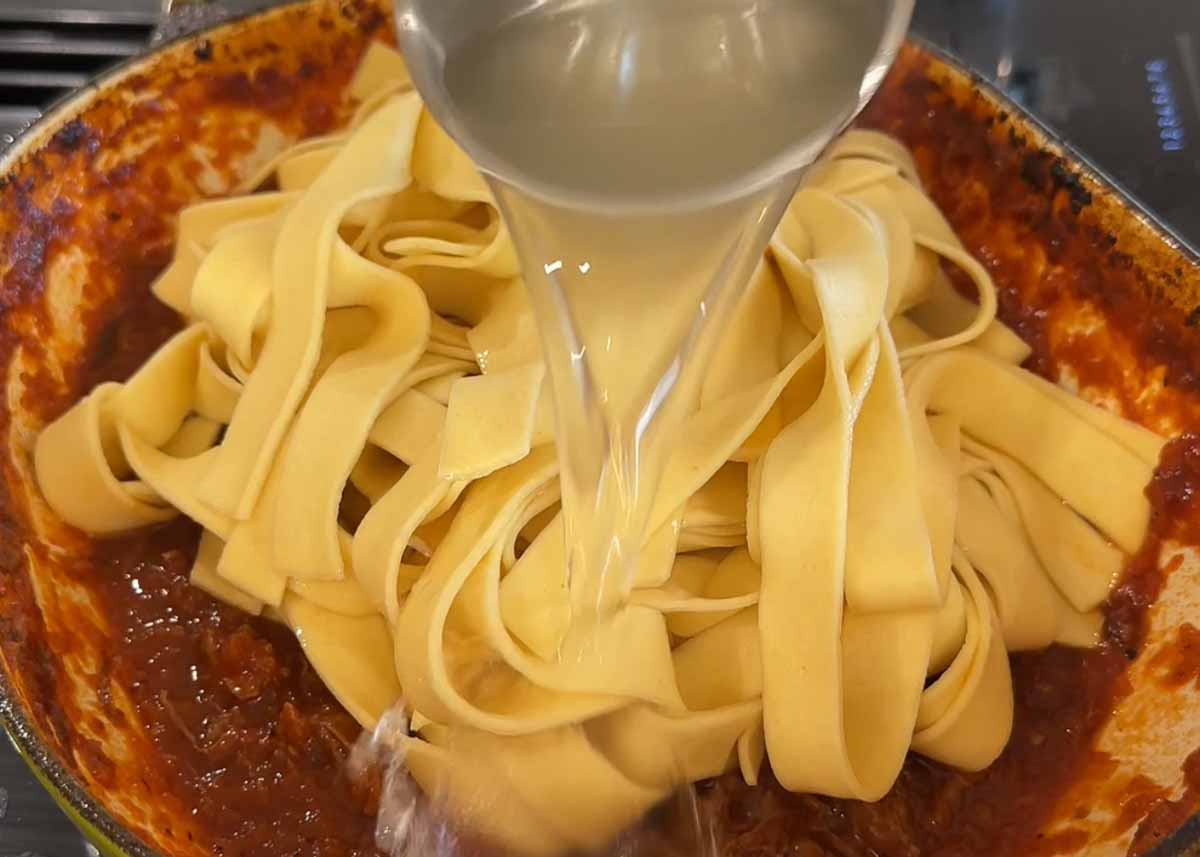 Fresh pappardelle being tossed through boneless lamb shank rosé ragu