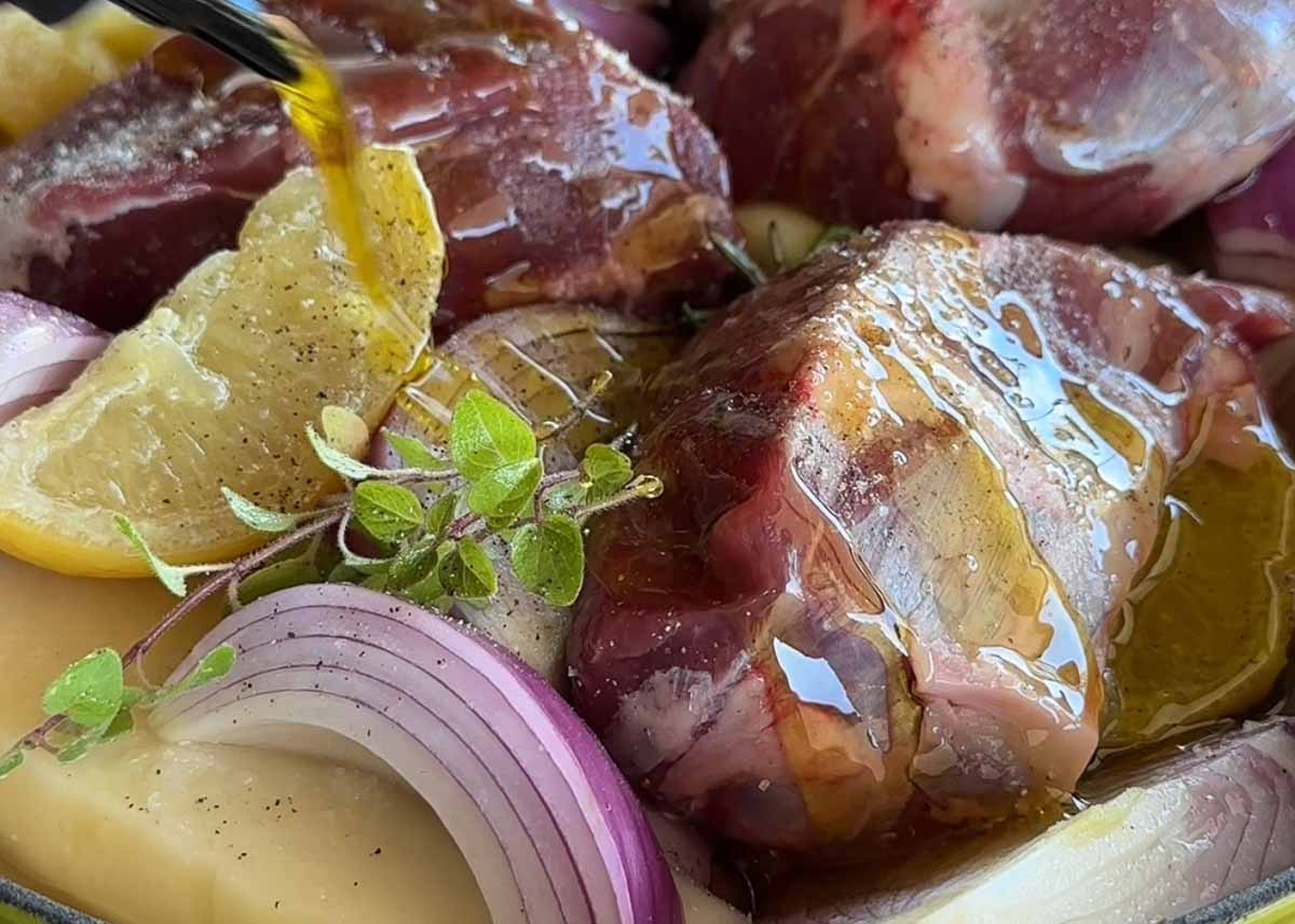 Raw boneless lamb shanks with preserved lemon and herbs before braising.