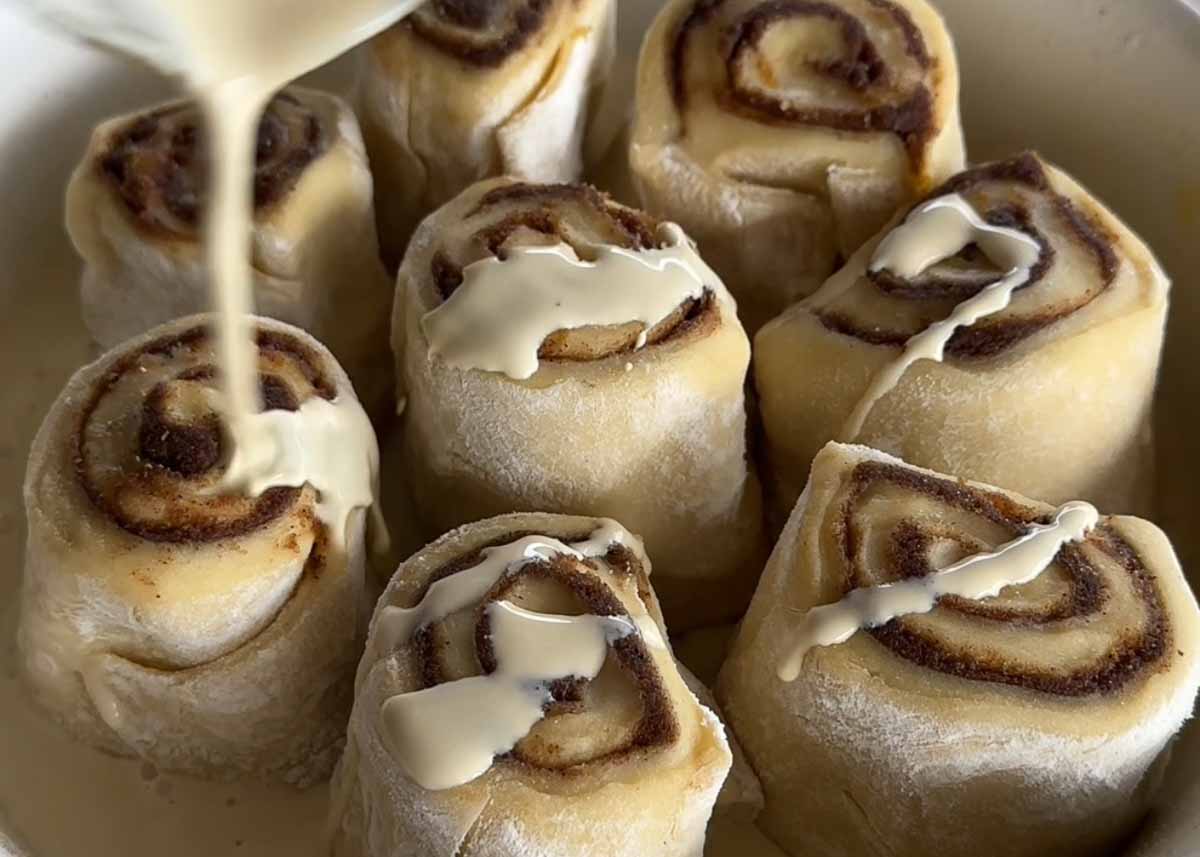 Cream being poured over sourdough scrolls before baking.