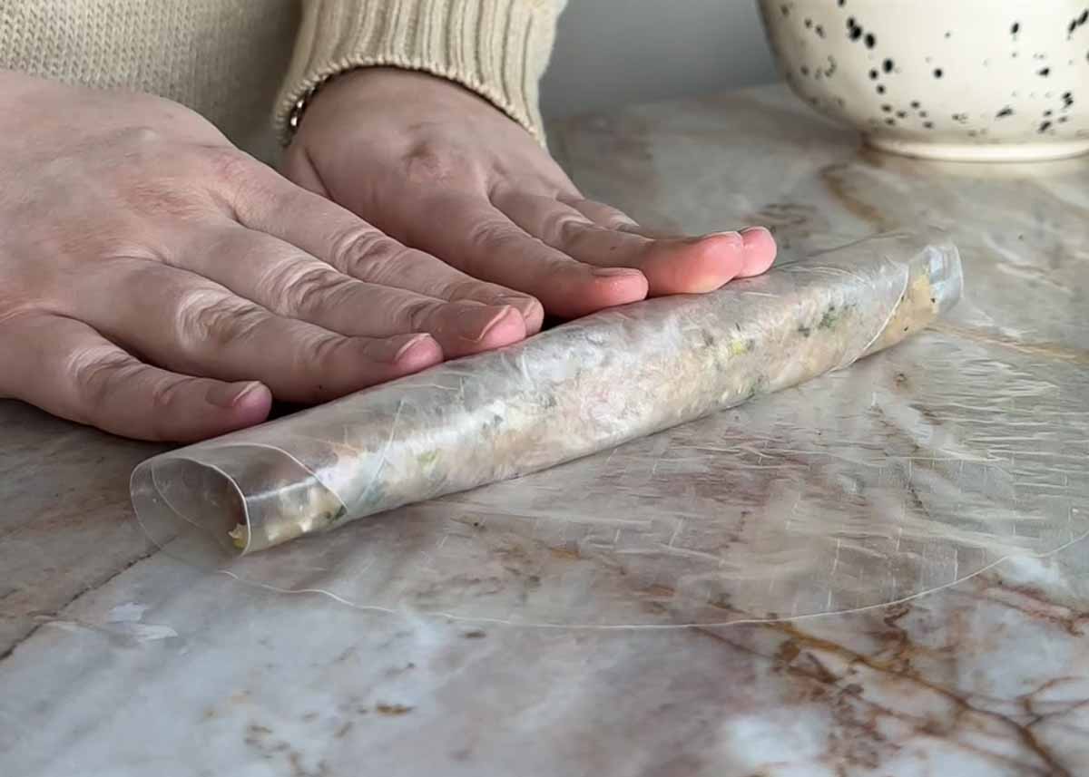 Wrapping chicken rice paper dumplings in a second layer of rice paper before slicing.