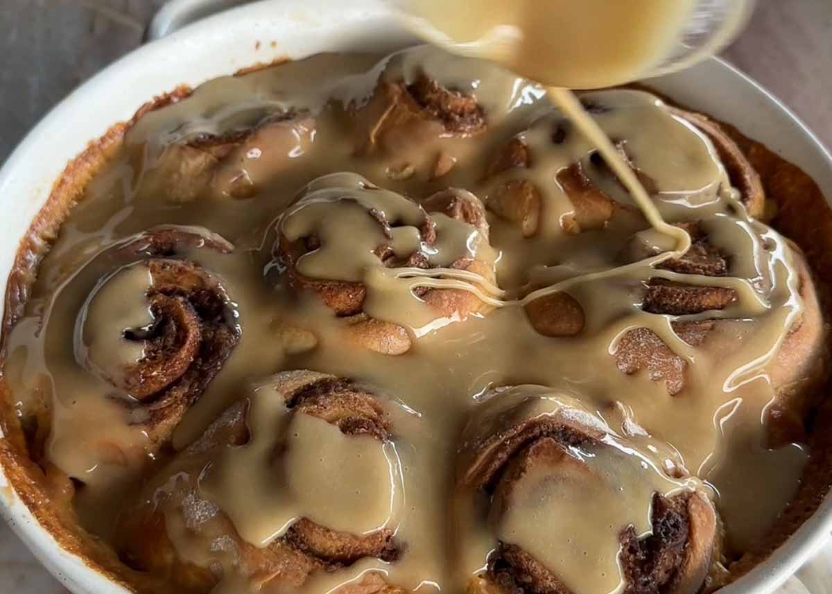 Salted maple glaze being drizzled over freshly baked brown butter cardamom scrolls.