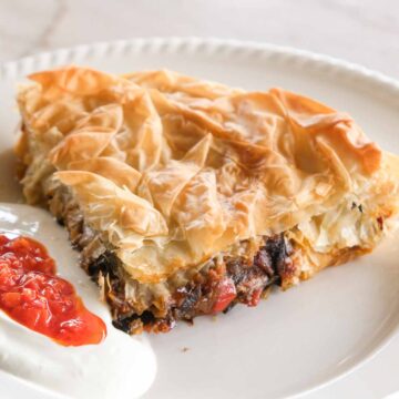 Slice of jammy eggplant börek filled with roasted eggplant, capsicum and caramelised onions in crisp golden filo pastry.