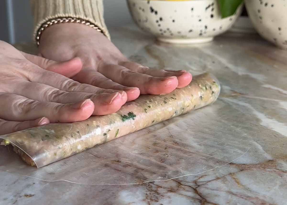 Rolling chicken filling inside softened rice paper to make dumplings.