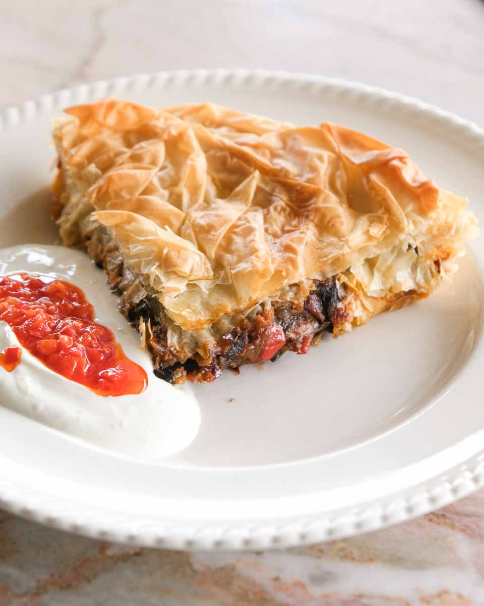 Slice of jammy eggplant börek filled with roasted eggplant, capsicum and caramelised onions in crisp golden filo pastry.