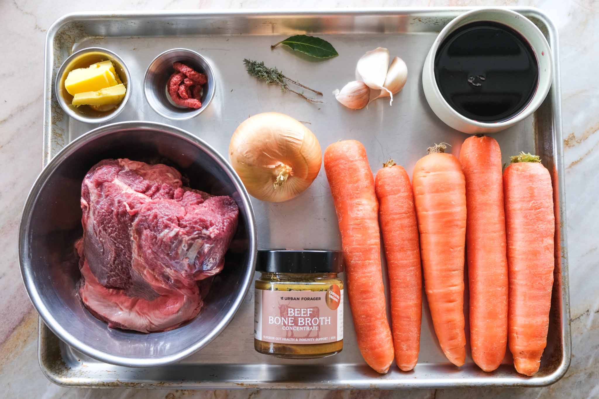 Ingredients for beef cheeks with carrot purée, including carrots, red wine, onion, garlic and herbs