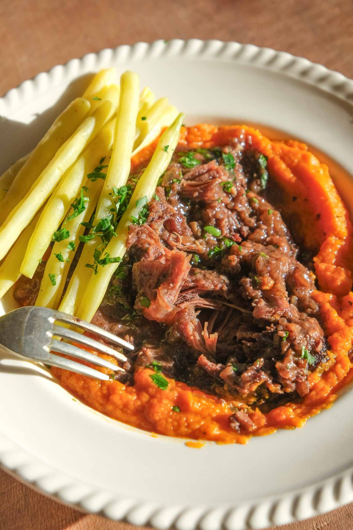 Tender braised beef cheek pulled apart over carrot purée with green beans